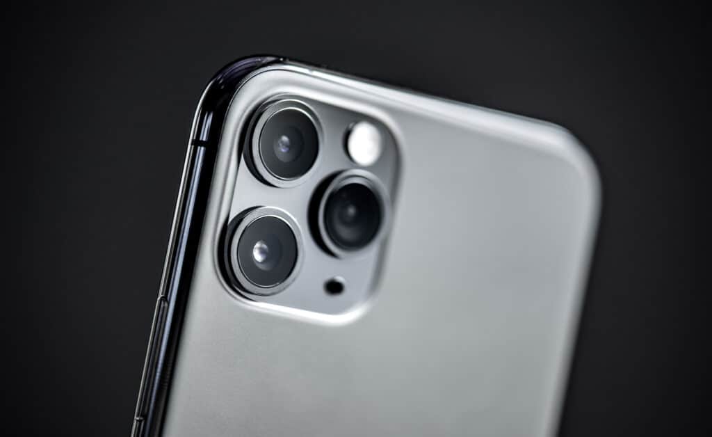 Silver smartphone with triple-lens camera system on a dark background.
